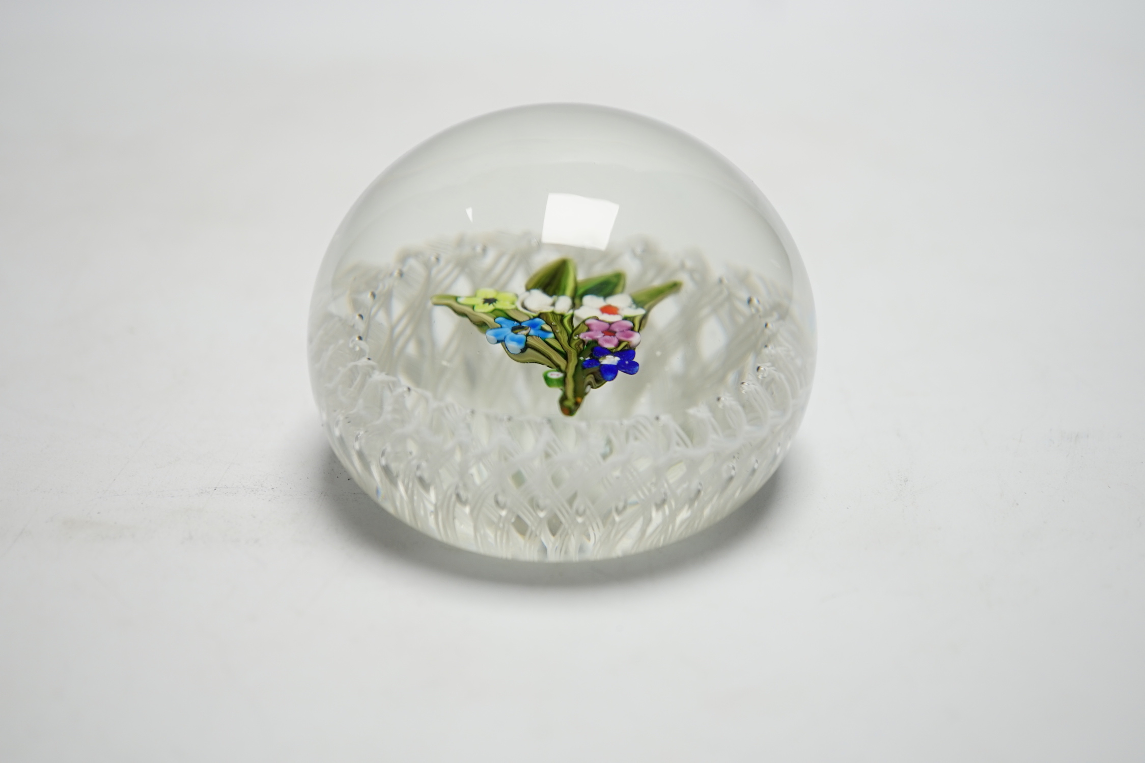 A Paul Ysart ‘small flower bouquet’ glass paperweight, Caithness or Harland period, ‘PY’ cane, white latticino ground, fire polished pontil, 7cm